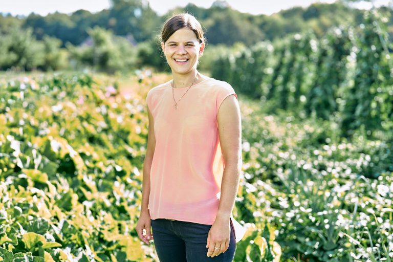 Stéphanie Würth steht vor einem üppig wachsenden Gemüsefeld.