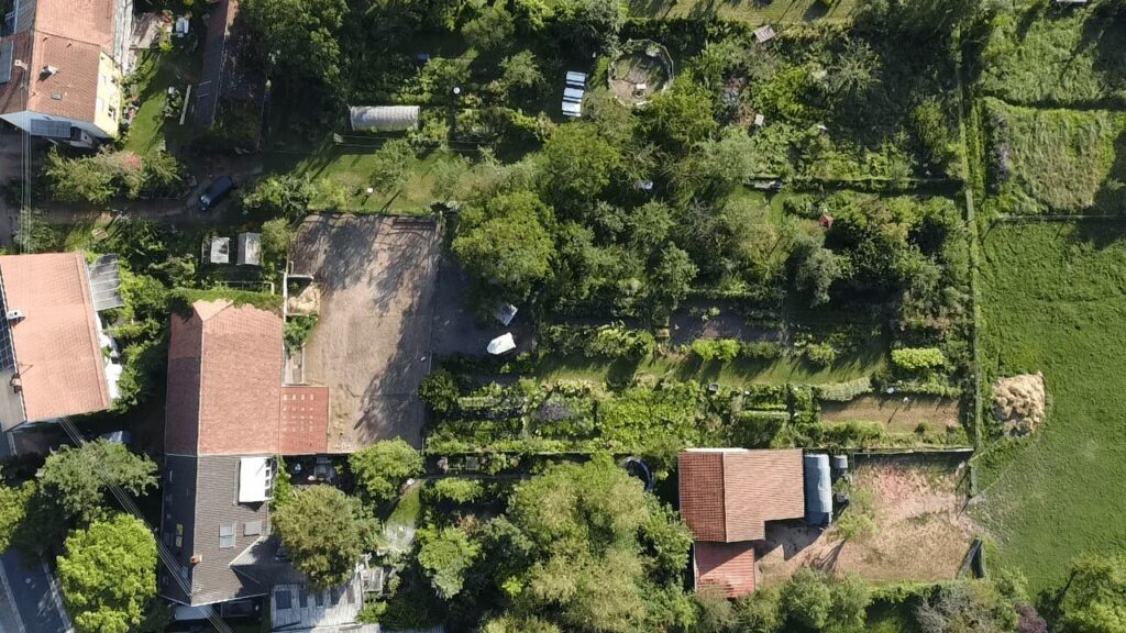 From the air, the Weltacker can be seen surrounded by houses. To the left, it borders agricultural fields. 