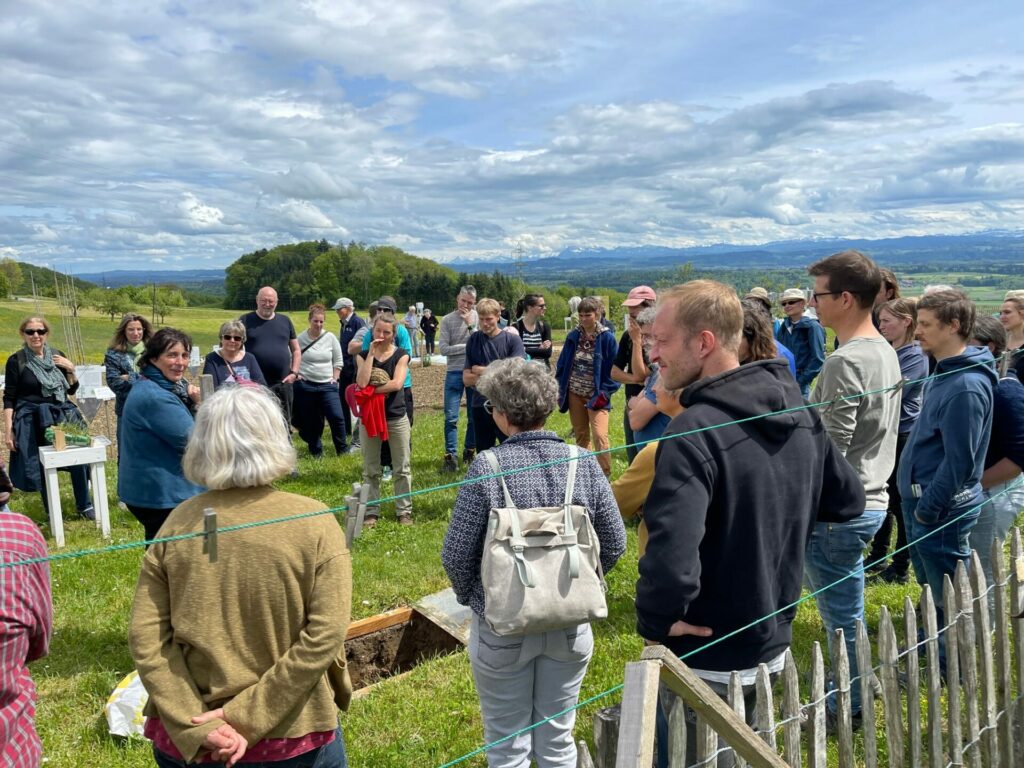 Viele Menschen lauschen während einer Ackertour den Ausführungen der Ackertour-Leiterin beim Bodenfenster.