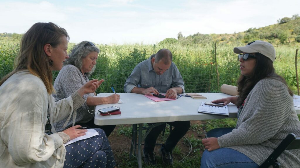 4 people sit ariund a table and discuss.