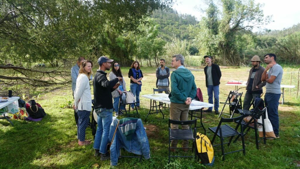 A group of people is standing around a table and talking to eachother. 