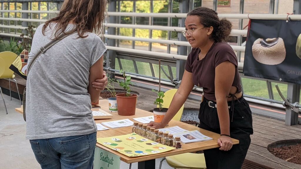 At an event, a woman looks with interest at the display about Global Bean and talks animatedly with the project employee.  