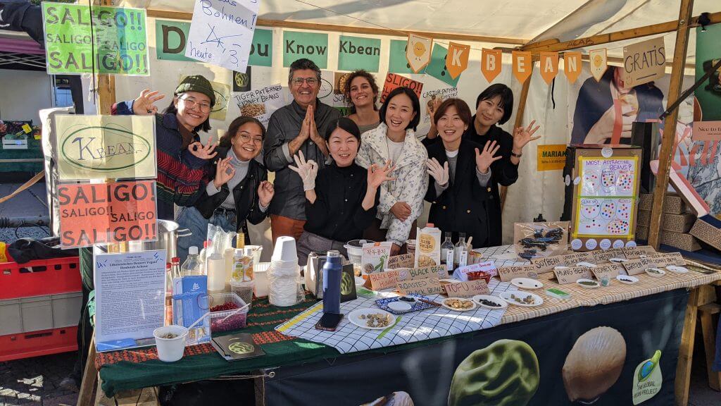 The Korean group Kbean, the Global Bean Team and a chef are together at the information table.