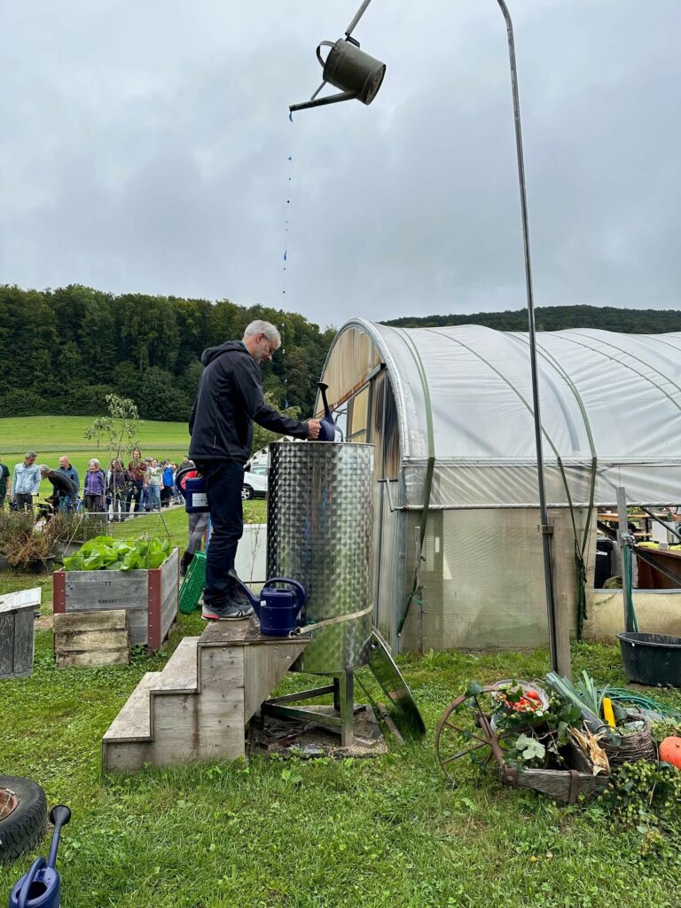 A visitor empties his watering can into a large barrel.