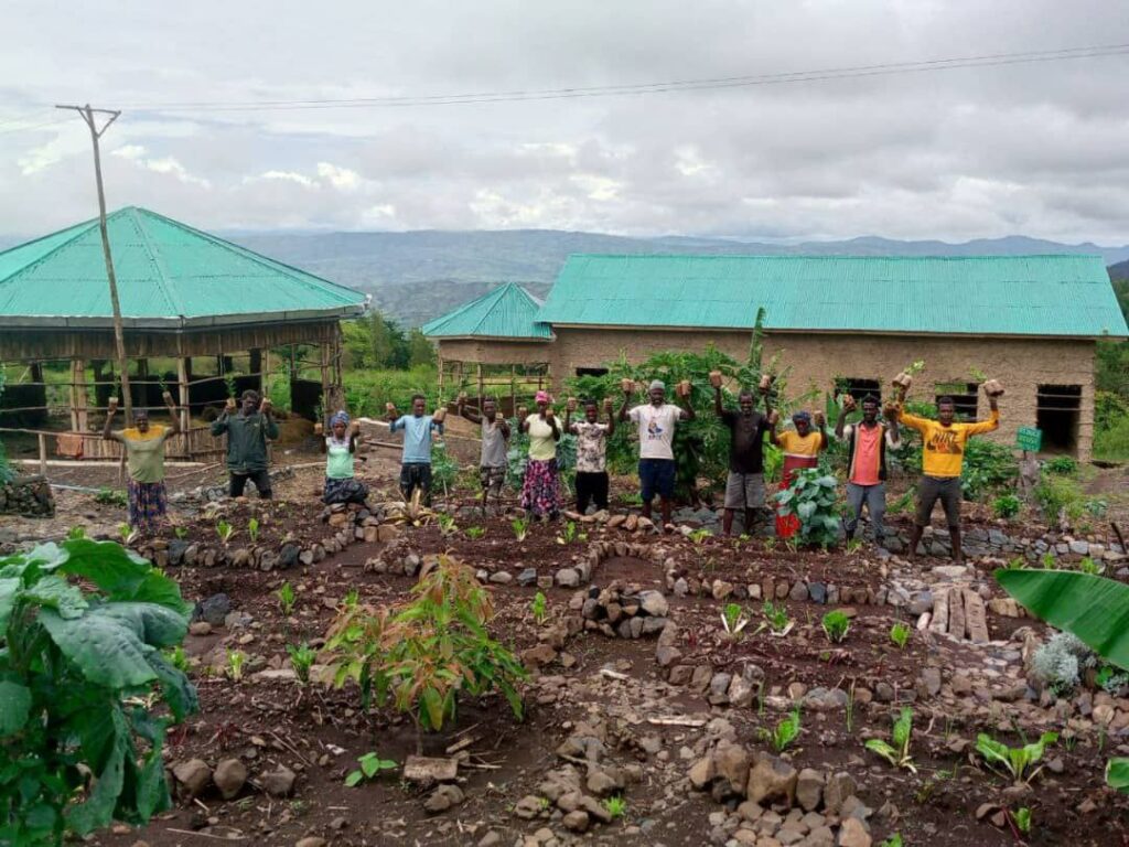 A group of farmers hold seedlings in the air and look into the camera. 